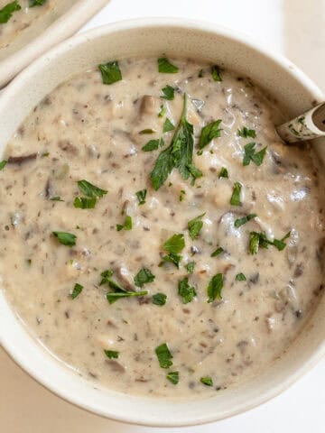 Creamy mushroom soup in a cup with a spoon.