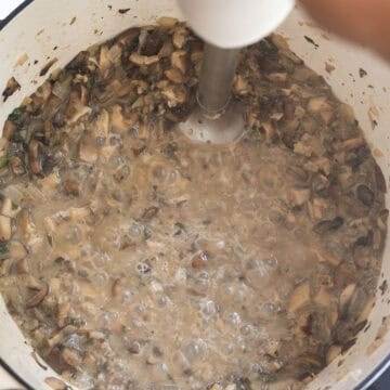 Blending the soup with an immersion blender.