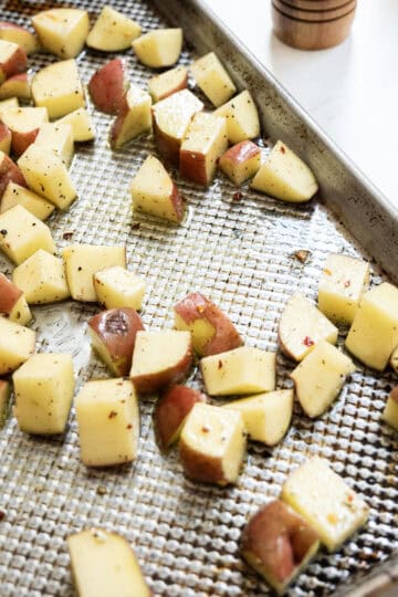 Potatoes added to baking tray.