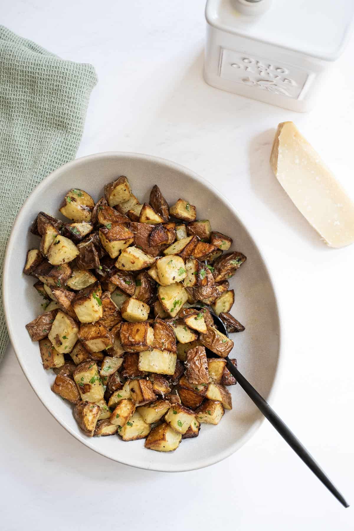 potatoes in a bowl next to parmesan and olive oil.