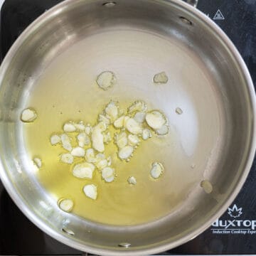 Garlic sauteing in olive oil in a pan.