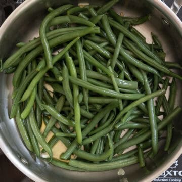 Green beans sauteing in pan with garlic.