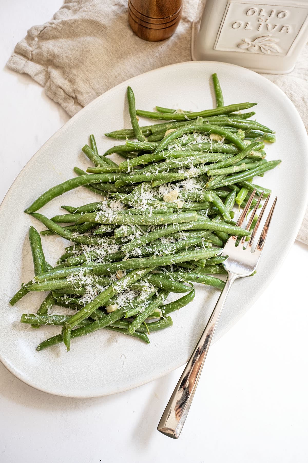 Sauteed green beans with garlic sprinkled with parmesan on a plate.