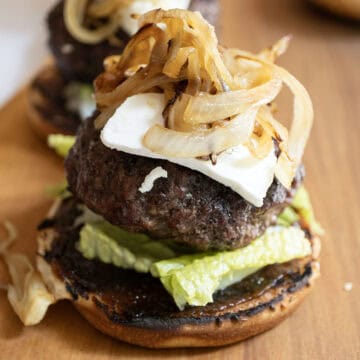 The burger on a bed of lettuce over fig jam, topped with goat cheese and caramelized onions.
