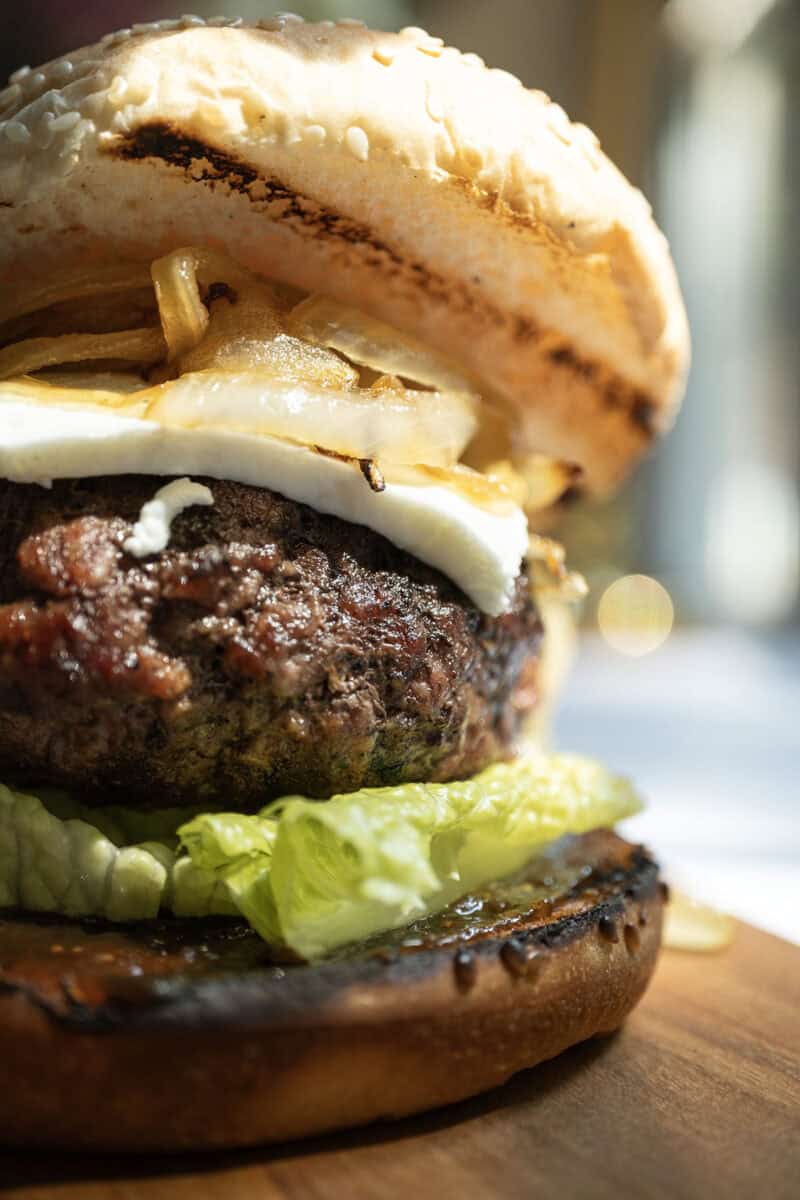 Burger on lettuce and fig jam topped with goat cheese and onions.