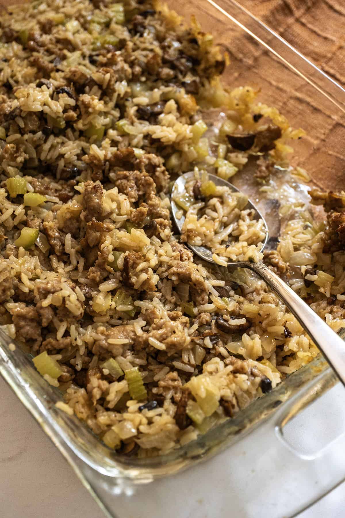 Rice dressing in an oven dish with a spoon.