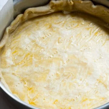 Pie crust with egg wash and fork holes pre-baked.