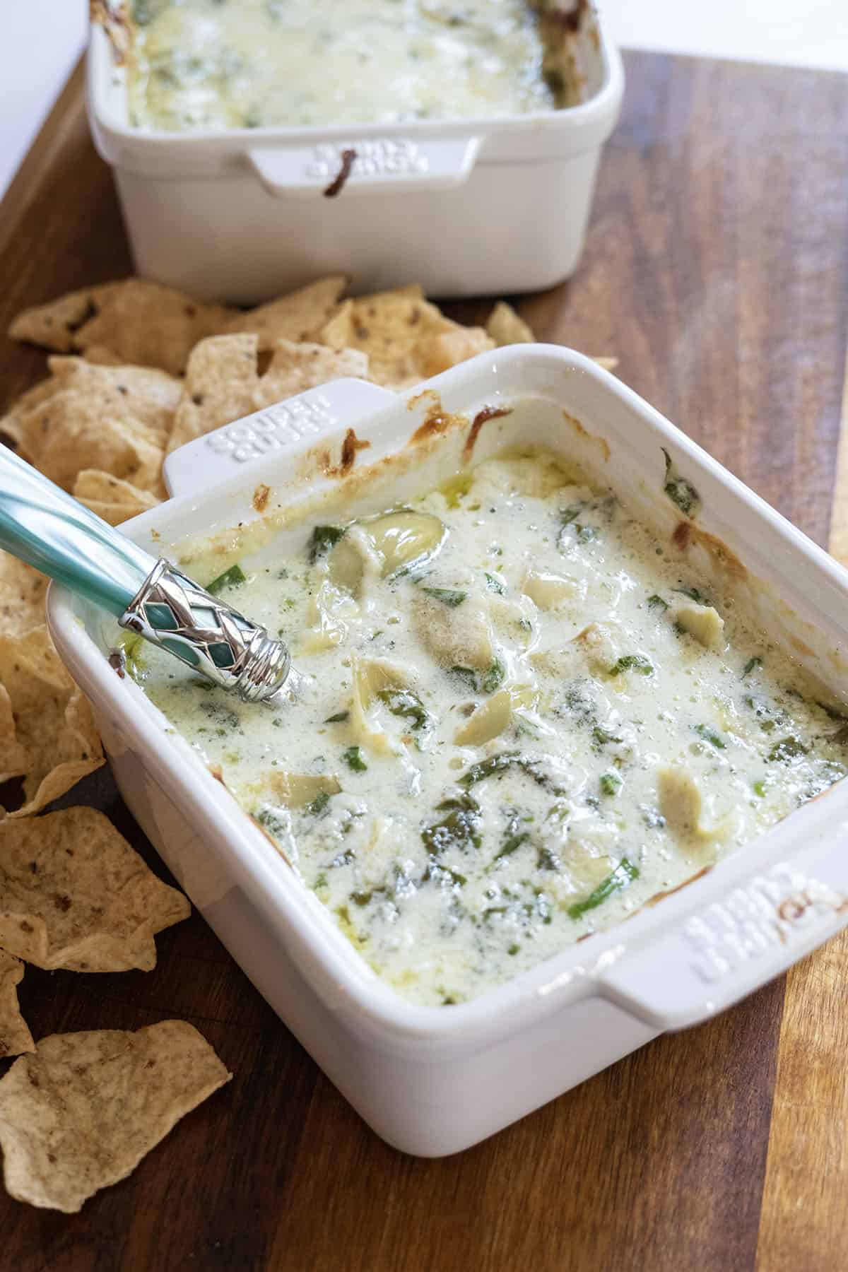 Spinach and artichoke dip in a dish with some tortilla chips next to it.
