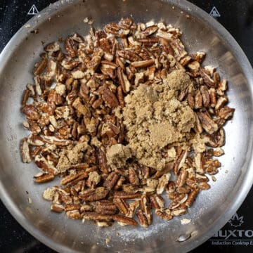 Combing pecans with brown sugar in a pan.