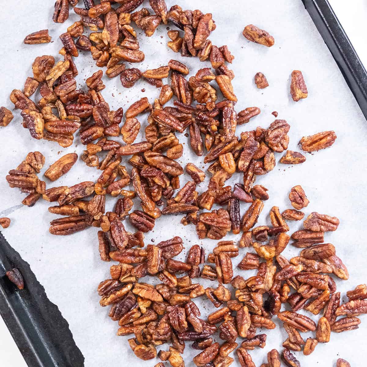 Pecans laid out on a parchment paper-lined baking tray.