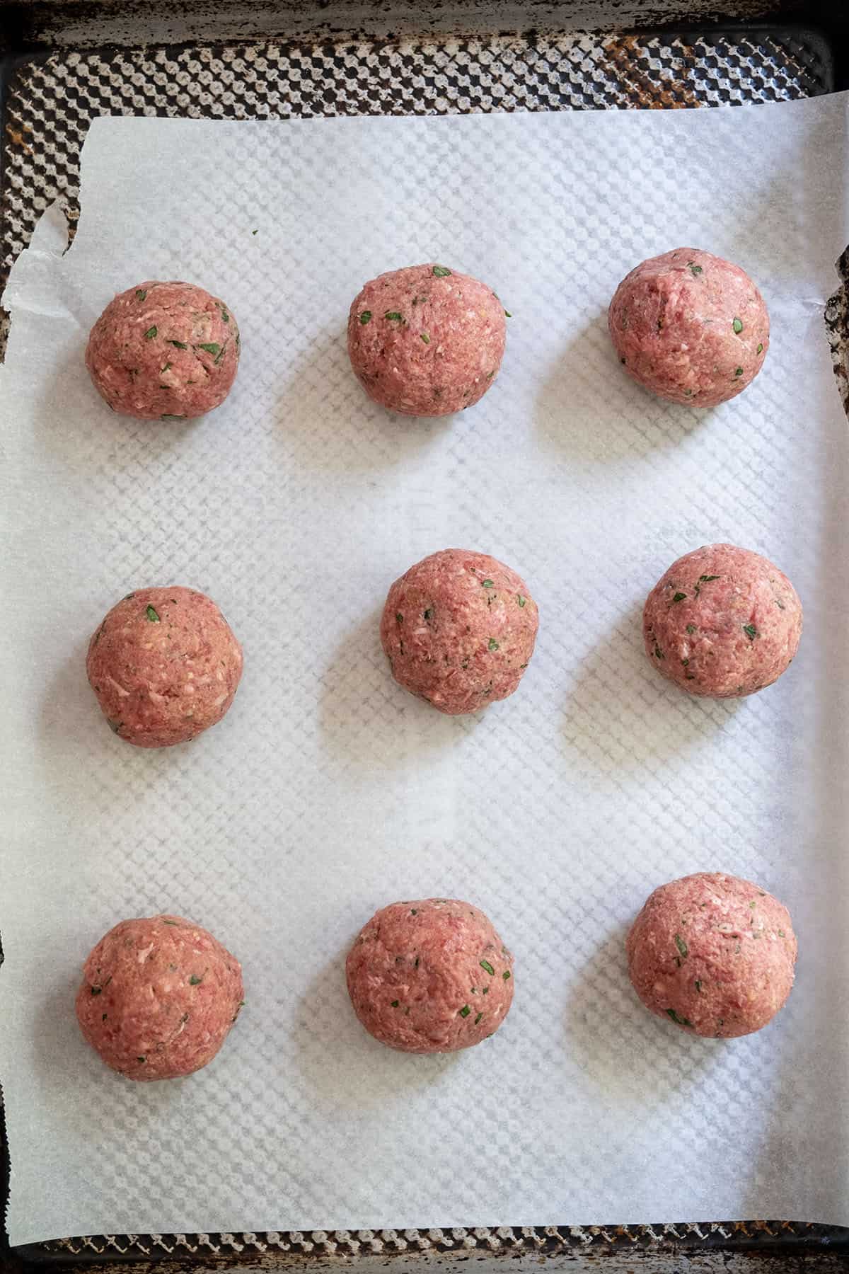 Raw meatballs on a baking sheet.