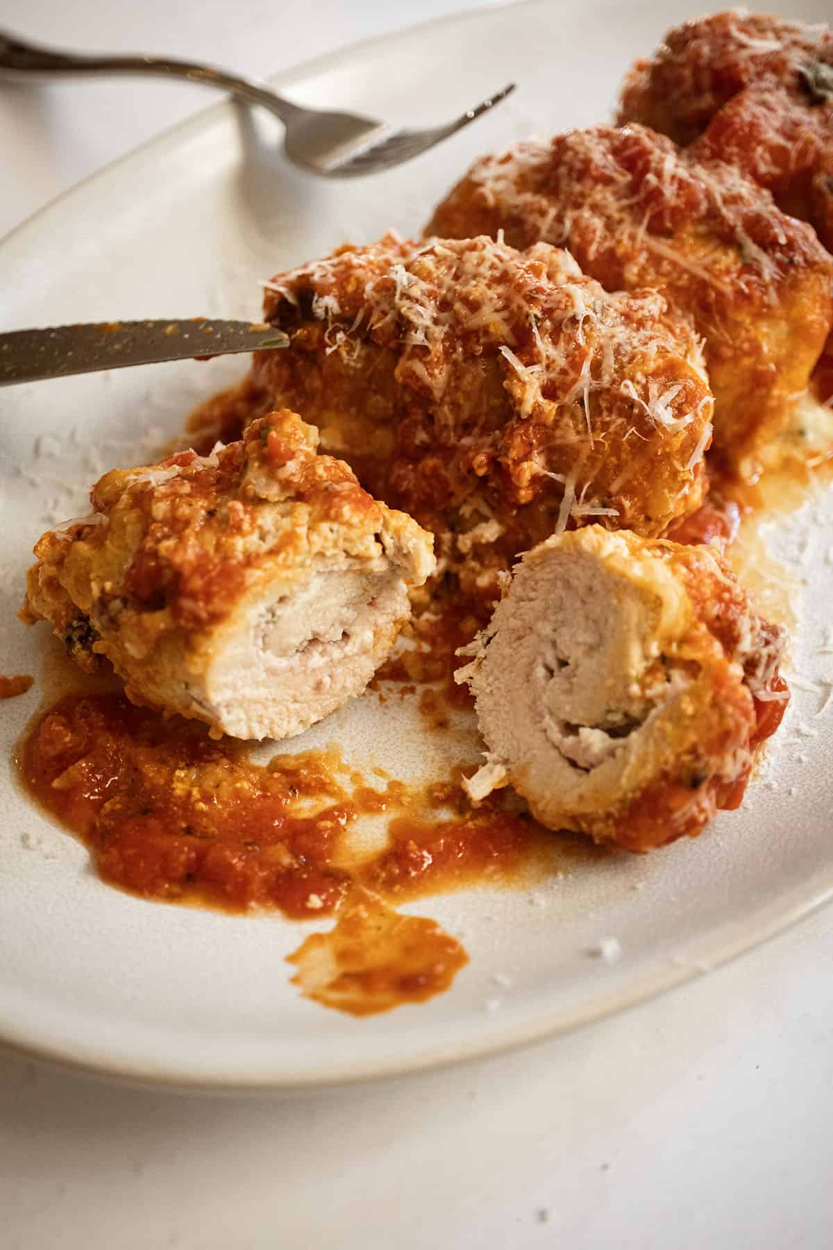 Chicken rollatini cut open with ricotta filling inside.