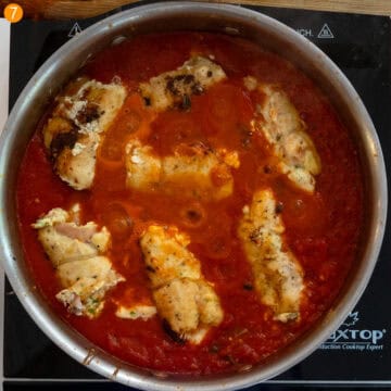 Chicken rollatini placed in the sauce to simmer.