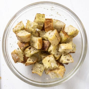 Bowl of chopped bread tossed in olive oil, garlic, and seasonings.