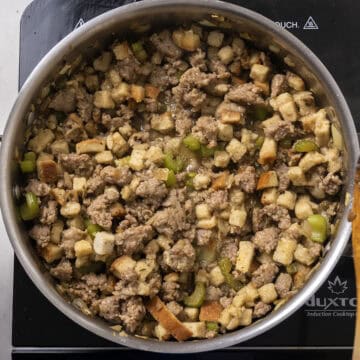 Stuffing cubes and chicken broth combined with brown sausage in a pan.