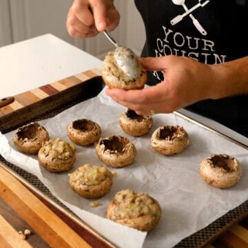 Stuffing mushrooms and placing them on a baking sheet.