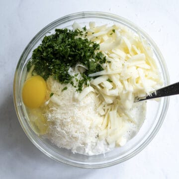 A bowl with ricotta, eggs, mozzarella, parsley, and parmesan cheese.