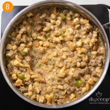 Italian sausage stuffing after the bread has absorbed the broth; some cubes remain intact while others have broken down into a creamy mixture.