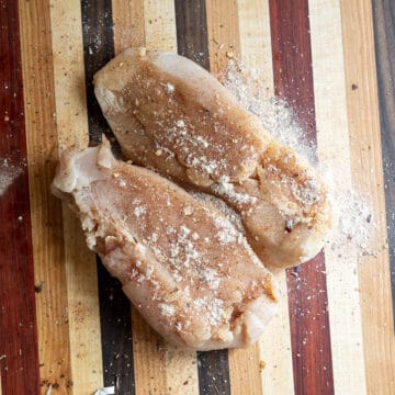 Seasoning the chicken on a cutting board.