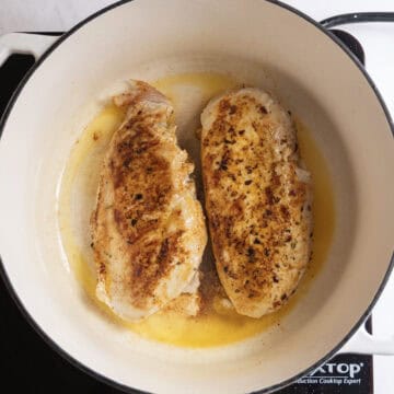 Searing the chicken to golden brown in the pot.
