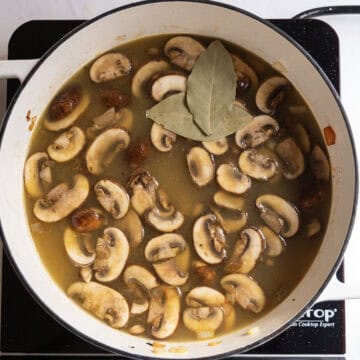 Broth added to the pot and simmering with bay leaves.