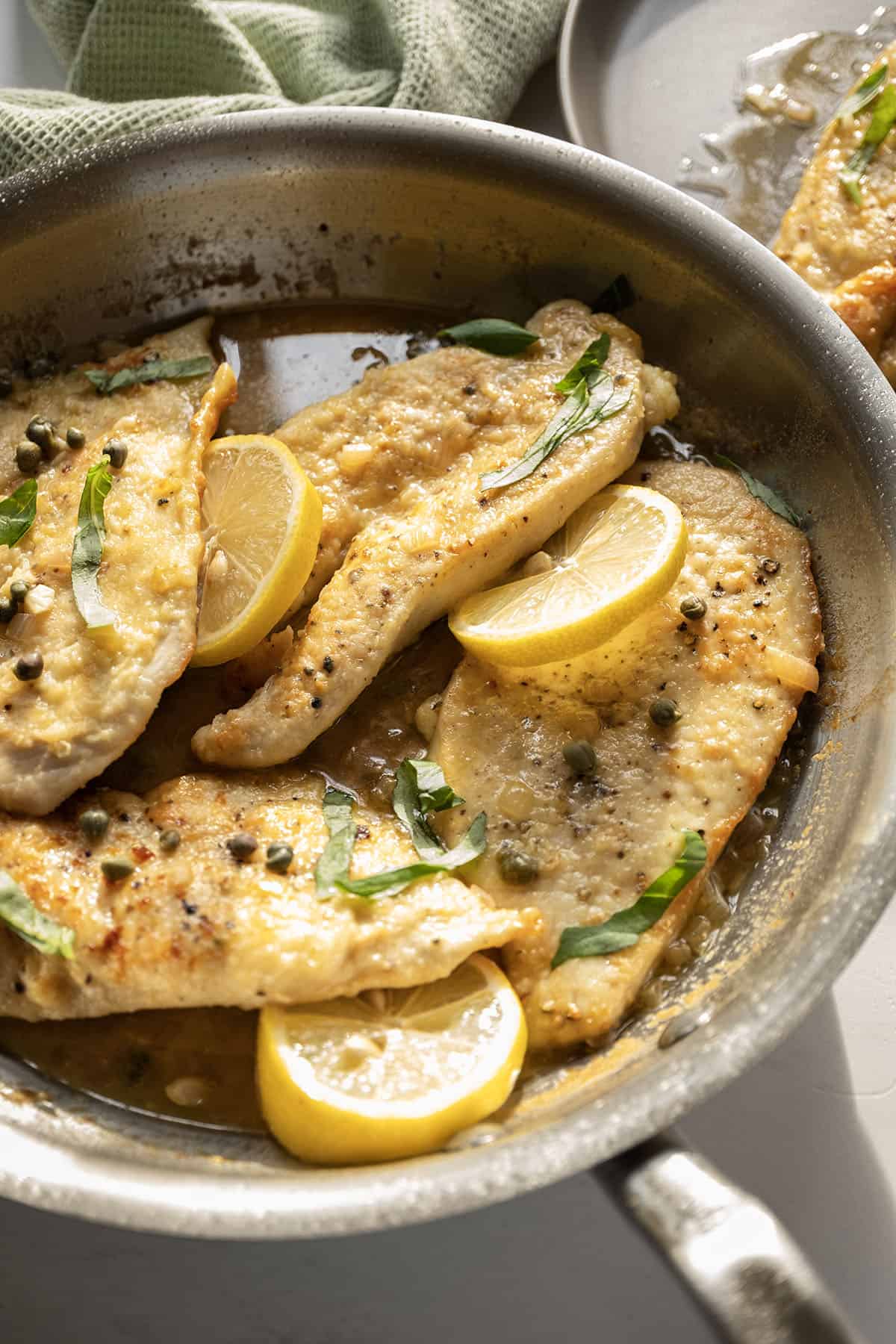 Chicken piccata in a saucepan with lemon and basil.