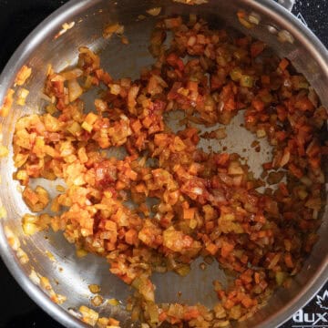 Tomato paste combined with vegetables in saucepan.