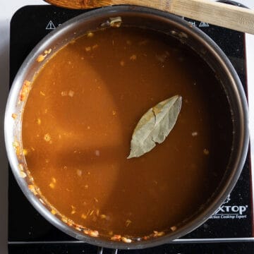 Chicken broth and bay leaf added to the saucepan.