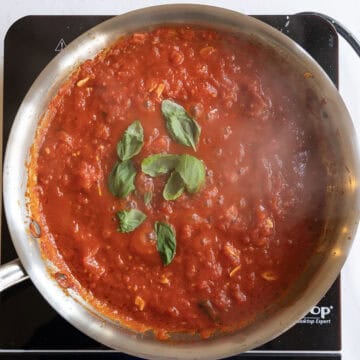 Fresh basil added to simmering tomato sauce.