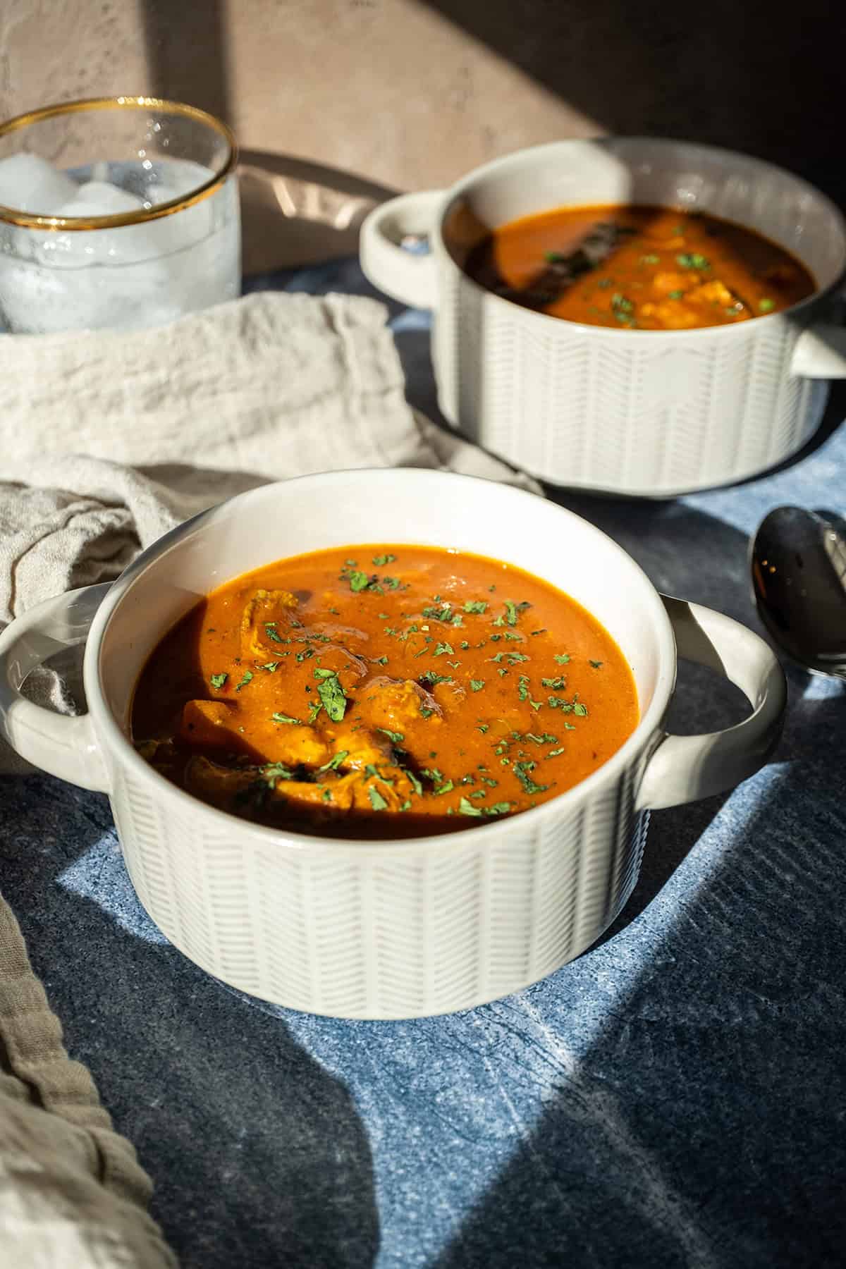 Butter chicken soup in a bowl topped with cilantro.