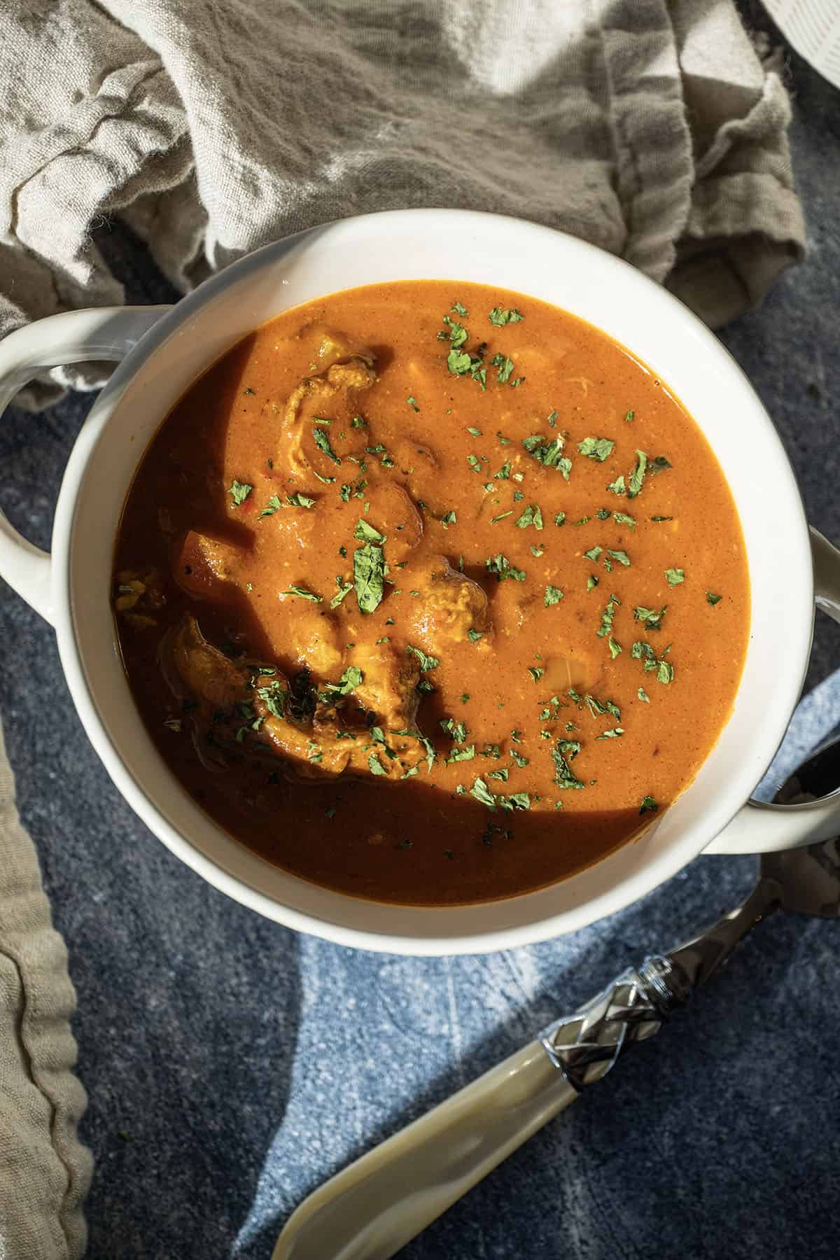 Butter chicken soup in a bowl topped with cilantro.