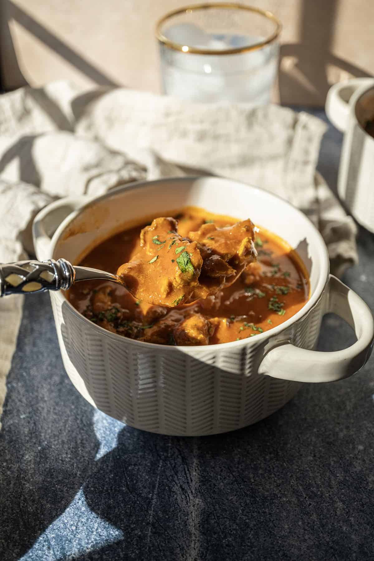 Butter chicken soup in a bowl topped with cilantro.