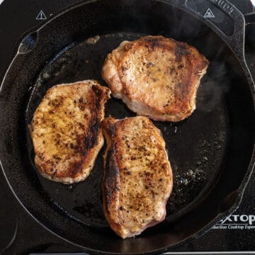 Searing pork chops on a cast iron flipped over.