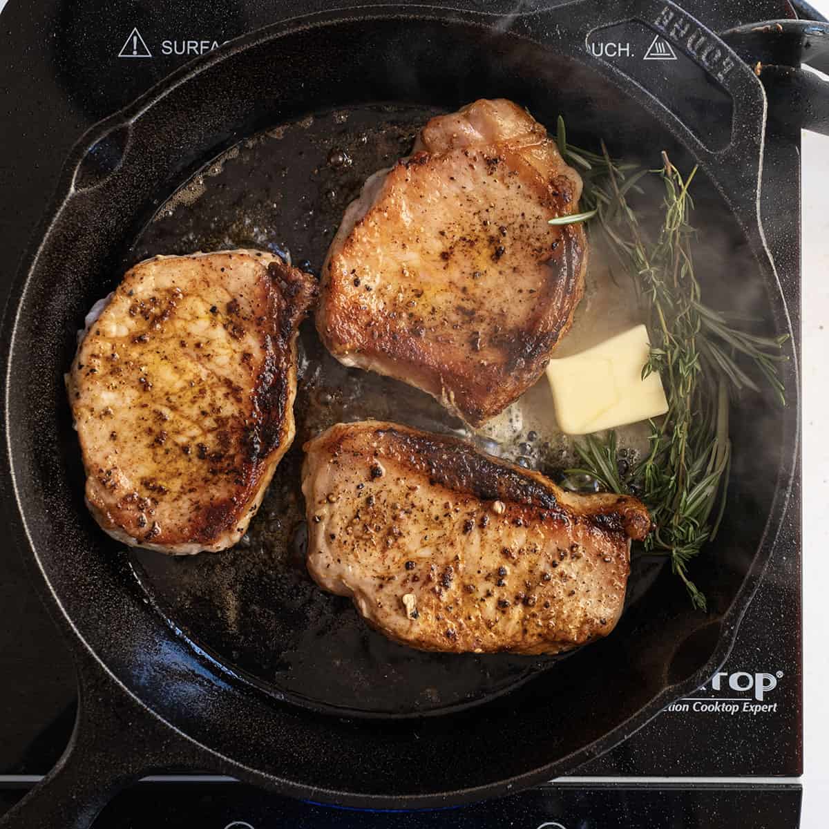 Seared pork chops basting in butter with thyme and rosemary.