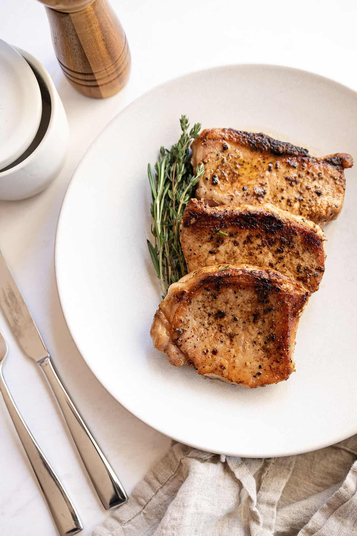 Boneless pork chops cooked on a plate with rosemary and thyme