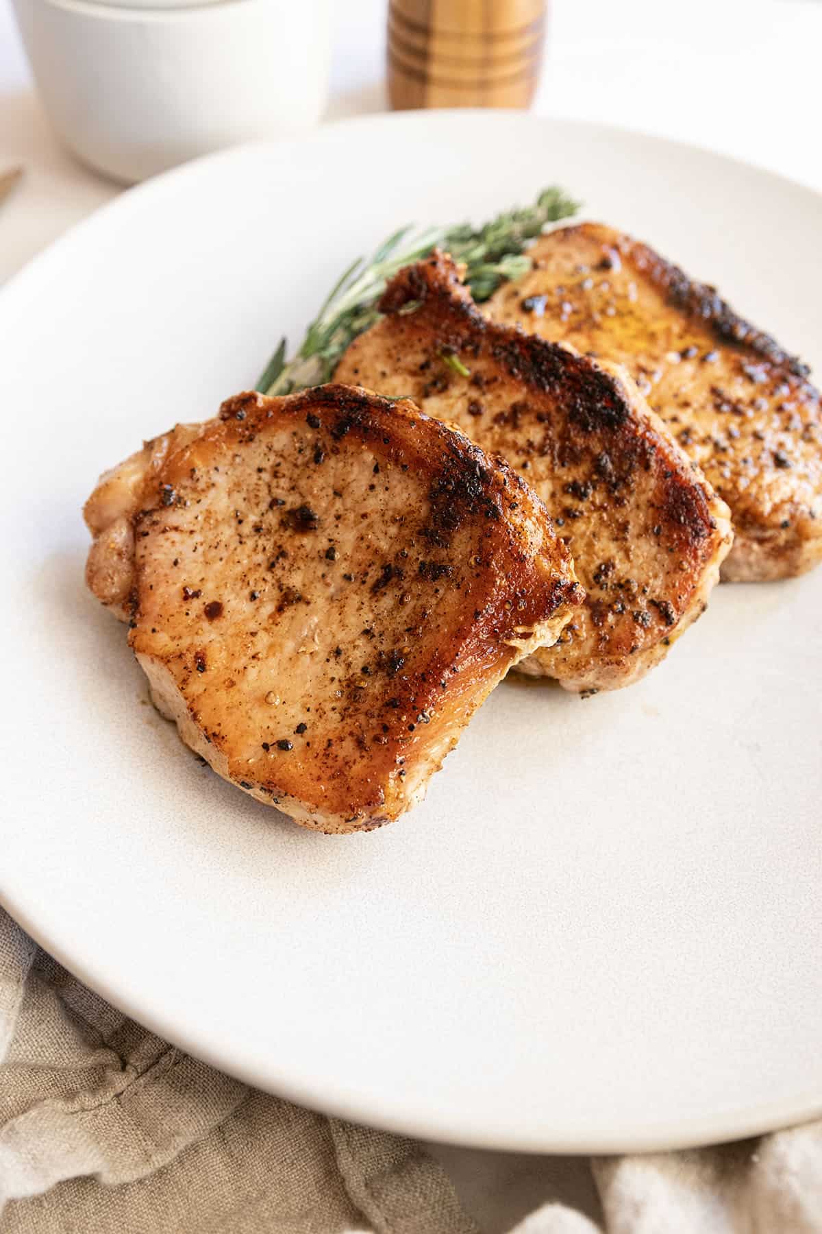 Boneless pork chops cooked on a plate with rosemary and thyme