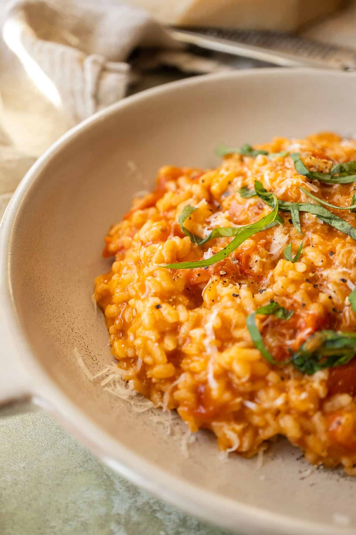 Creamy cherry tomato risotto in a bowl topped with fresh basil.