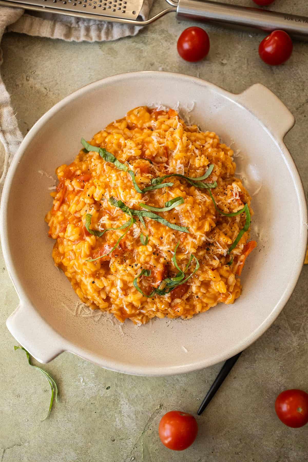 Creamy cherry tomato risotto in a bowl topped with fresh basil.