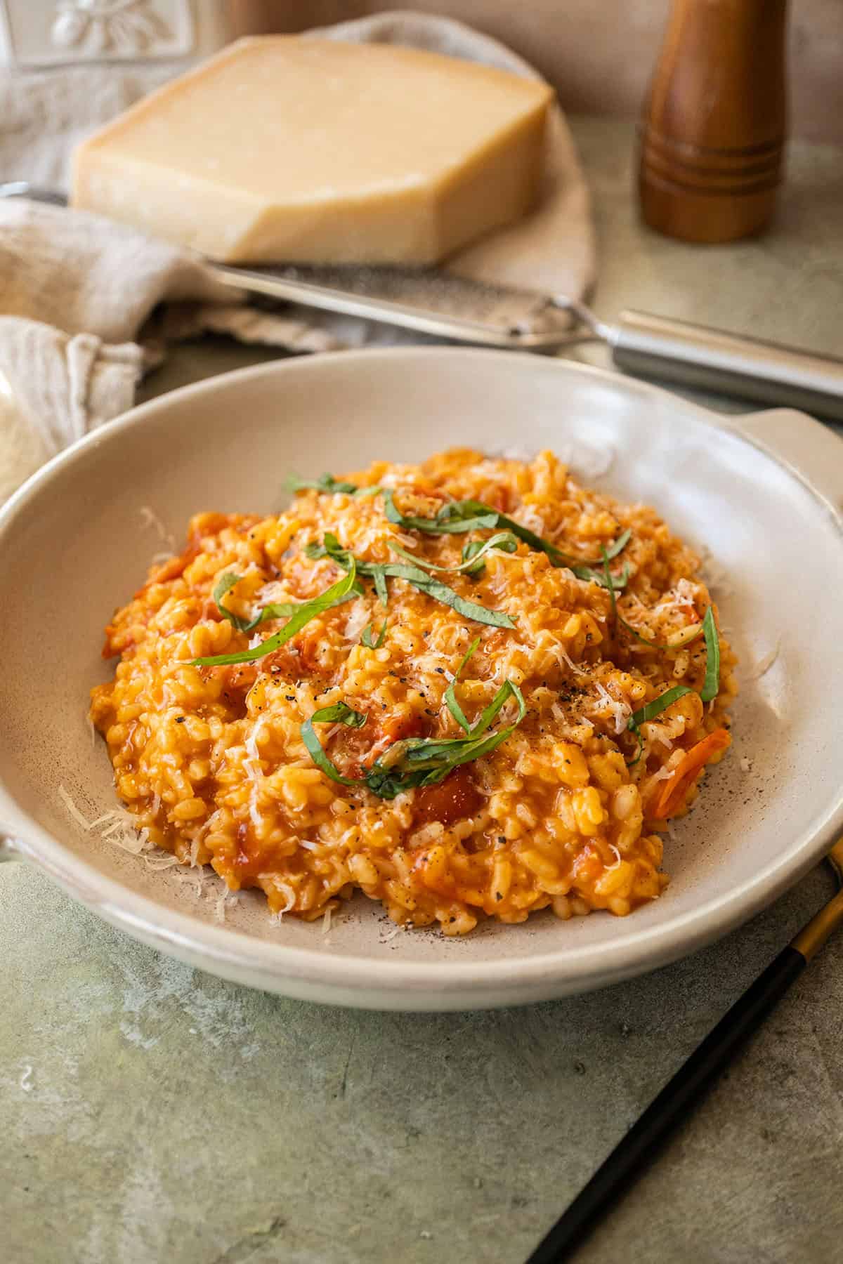 Creamy cherry tomato risotto in a bowl topped with fresh basil.