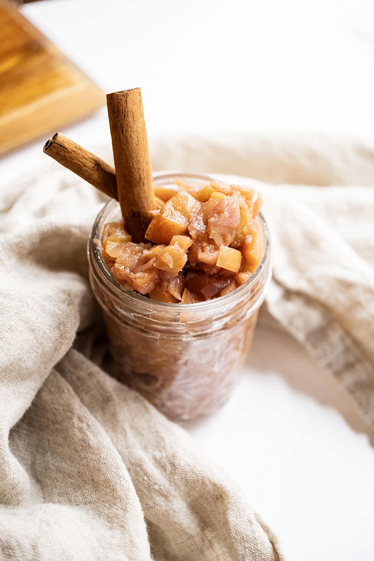 Spiced apple chutney in a mason jar garnished with cinnamon sticks.