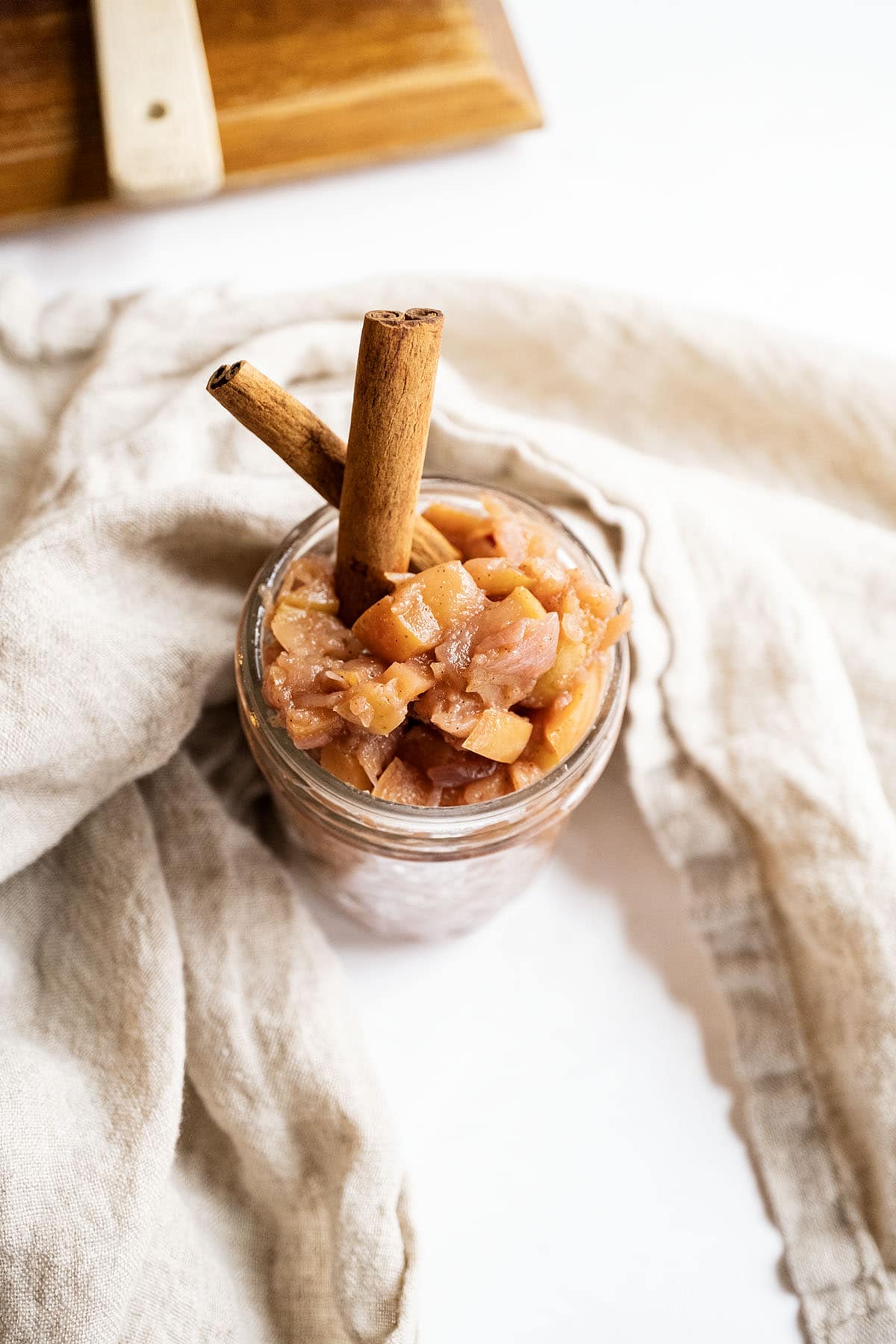 Spiced apple chutney in a mason jar garnished with cinnamon sticks.