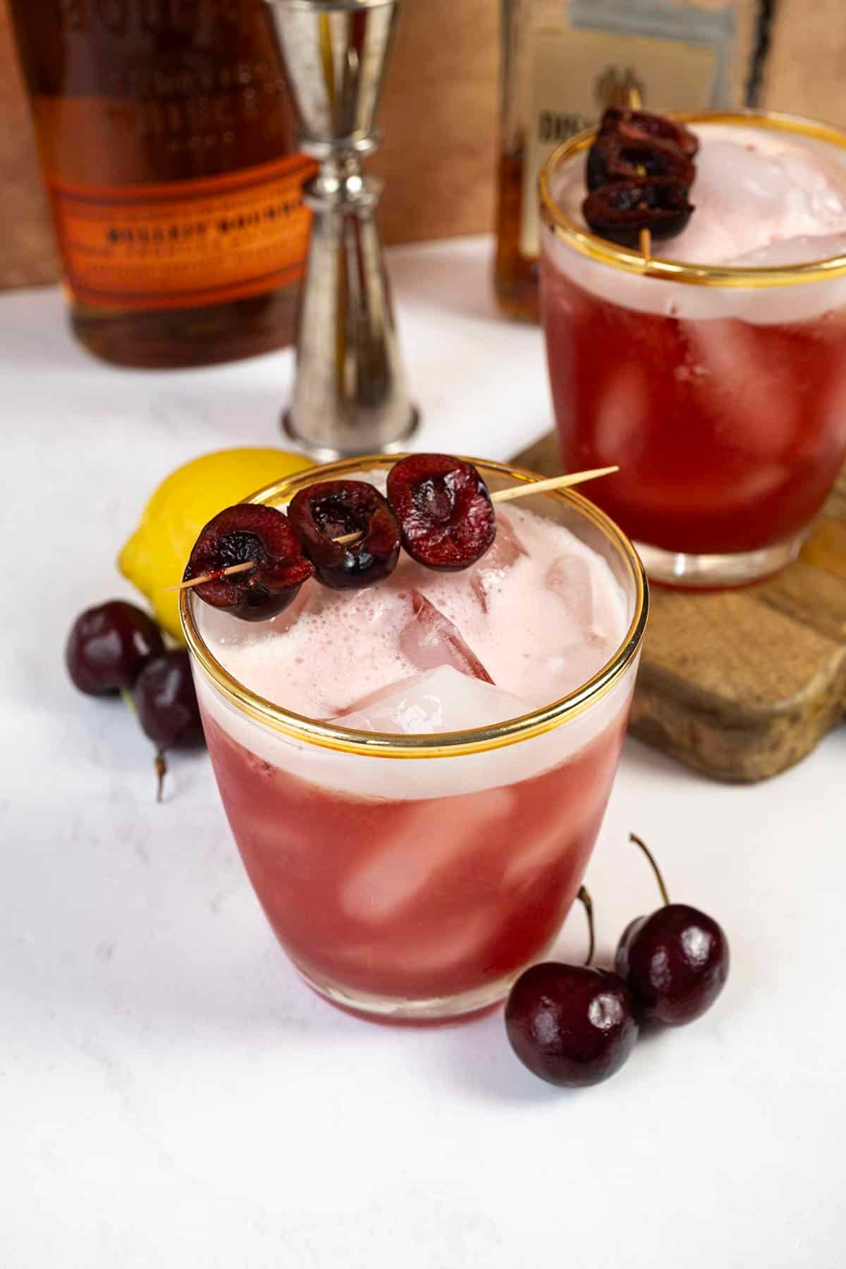 Cherry amaretto sour in a glass with a cherry garnish.