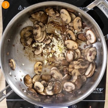 Sauteed mushrooms with garlic added in pan.