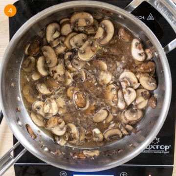 Simmering white wine with mushrooms in pan.