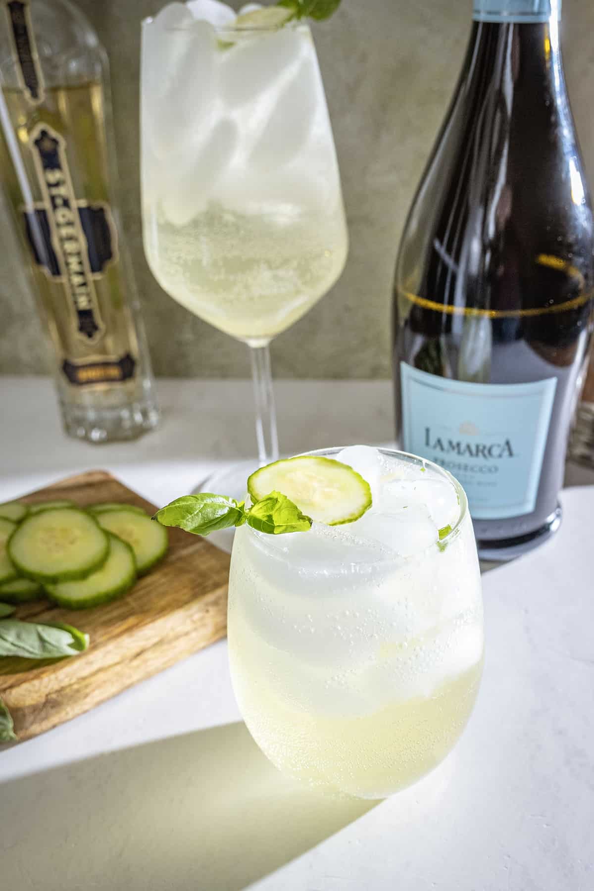 St germain spritz with cucumber and basil garnish.