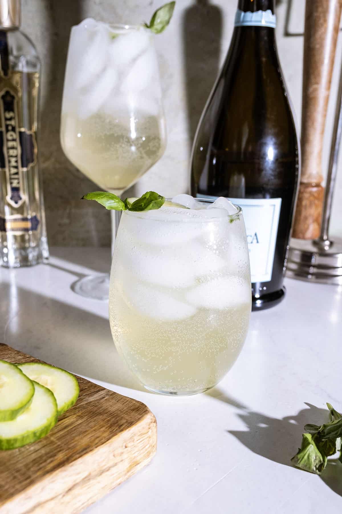 St germain spritz with cucumber and basil garnish.