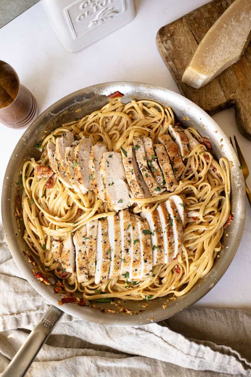 Creamy pasta in a pan topped with golden brown chicken.
