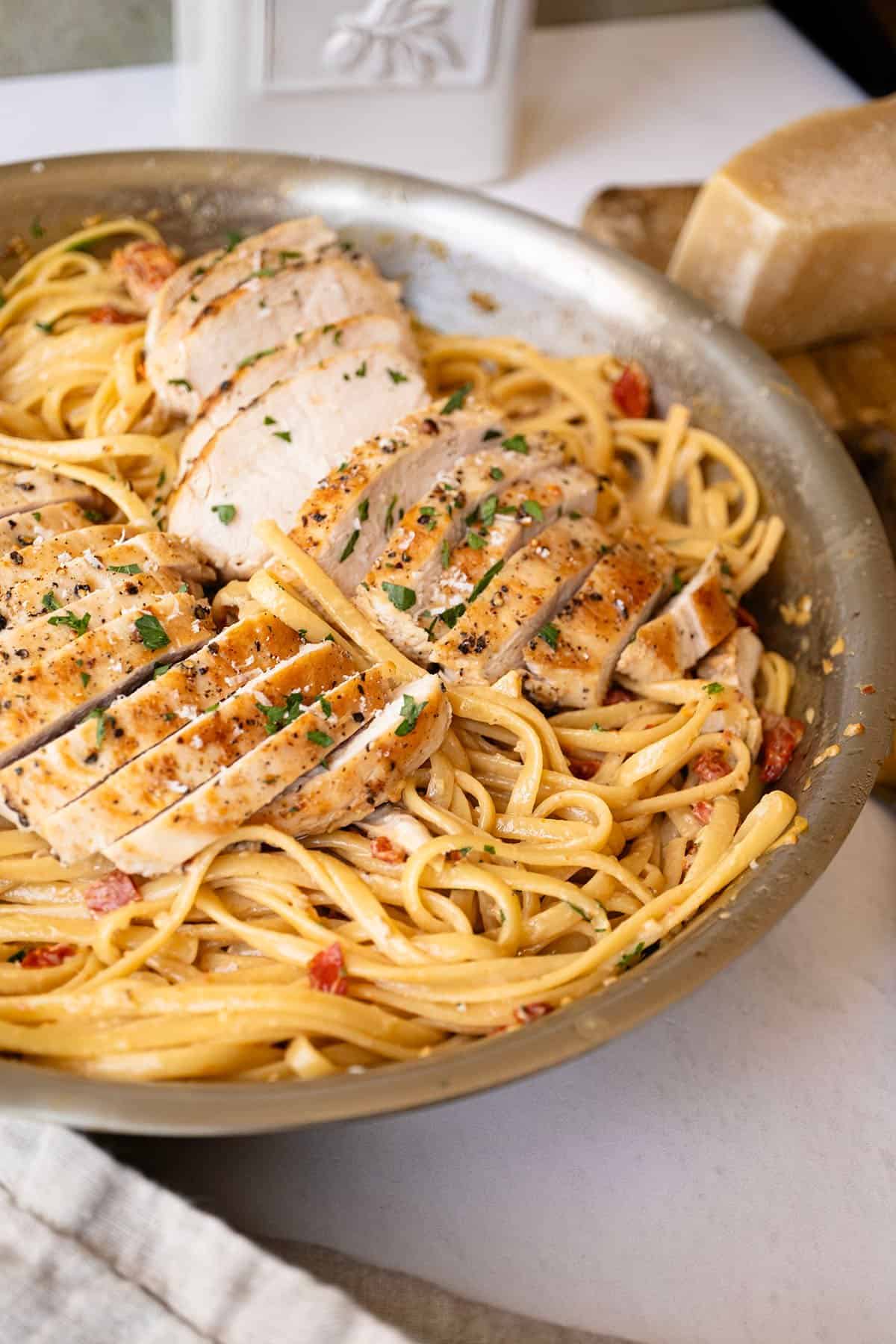 Creamy pasta in a pan topped with golden brown chicken.
