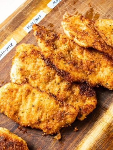 Chicken cutlets on a cutting board.