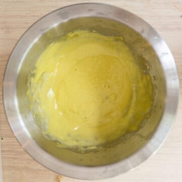 Pale yellow garlic aioli whisked together in a bowl.